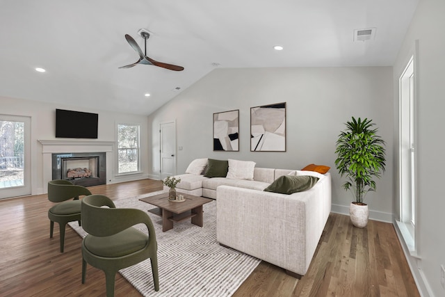 living area featuring visible vents, vaulted ceiling, and wood finished floors