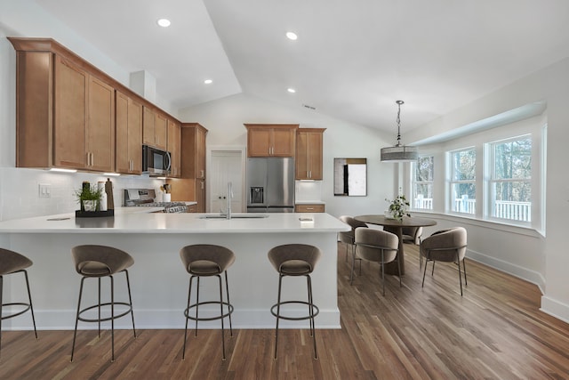 kitchen with hanging light fixtures, brown cabinetry, appliances with stainless steel finishes, and light countertops