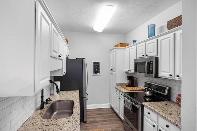 kitchen featuring backsplash, dark wood-type flooring, appliances with stainless steel finishes, and white cabinets