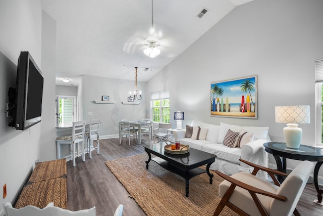 living room with a healthy amount of sunlight, dark hardwood / wood-style flooring, high vaulted ceiling, and ceiling fan with notable chandelier