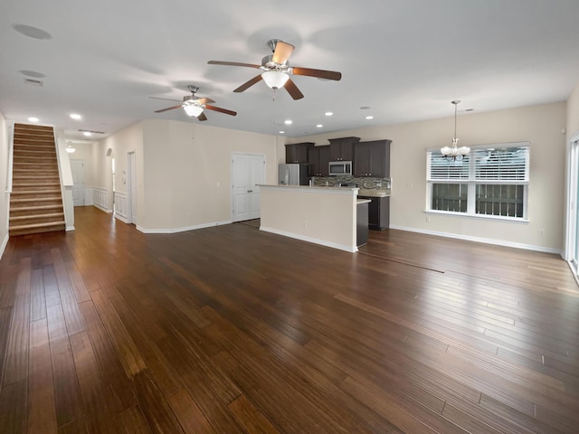 unfurnished living room with dark hardwood / wood-style flooring and ceiling fan with notable chandelier