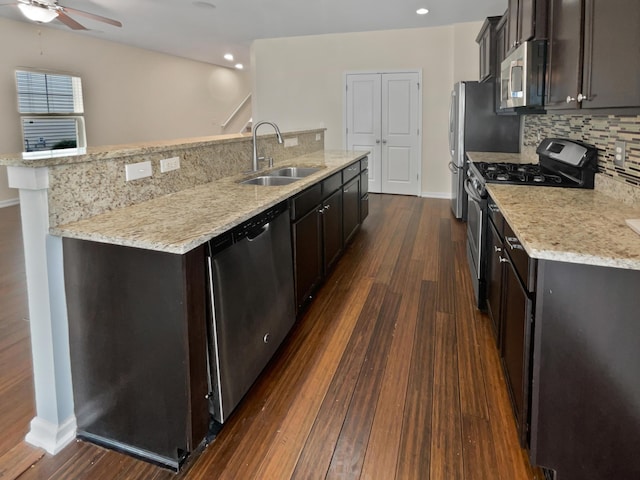 kitchen with appliances with stainless steel finishes, dark wood-type flooring, decorative backsplash, sink, and a center island with sink