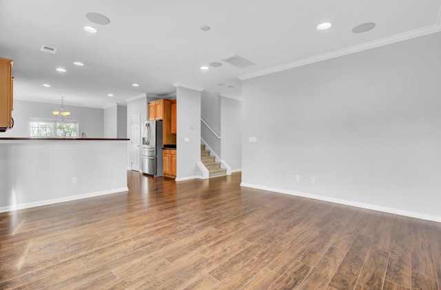 unfurnished living room with hardwood / wood-style flooring, a notable chandelier, and ornamental molding