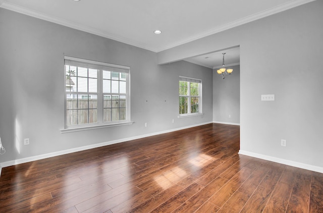 spare room with an inviting chandelier, dark hardwood / wood-style flooring, and ornamental molding