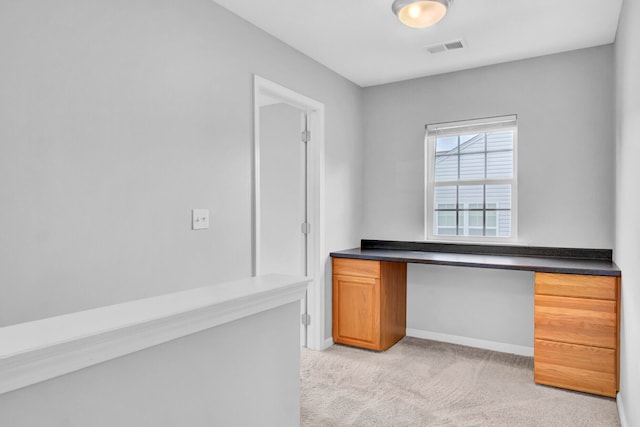 unfurnished office featuring light colored carpet and built in desk