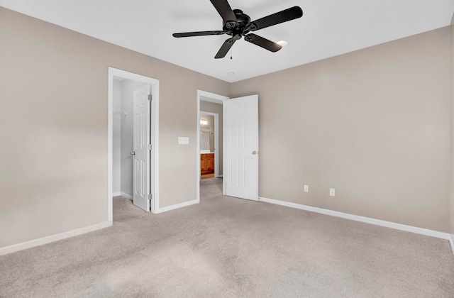 unfurnished bedroom featuring a closet, light carpet, a walk in closet, and ceiling fan