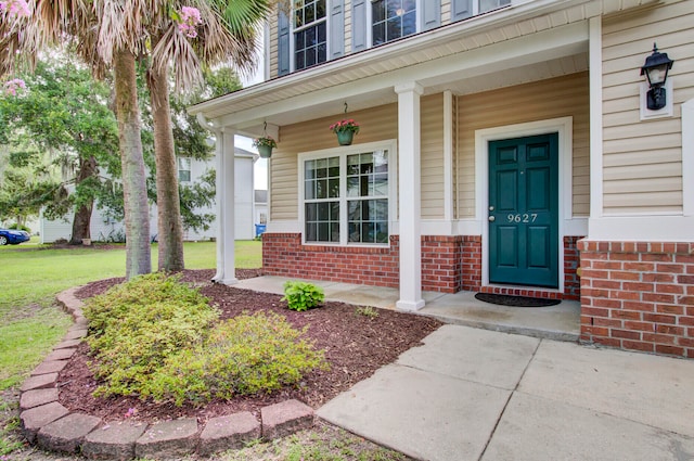 property entrance featuring a lawn and covered porch