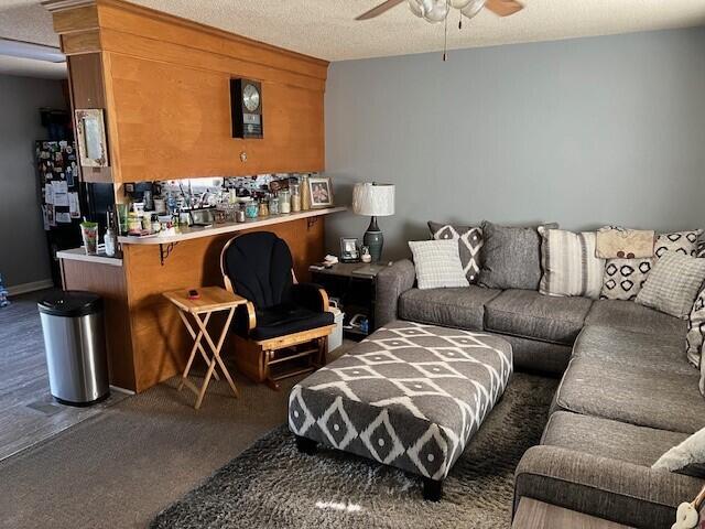 carpeted living room featuring a textured ceiling and ceiling fan