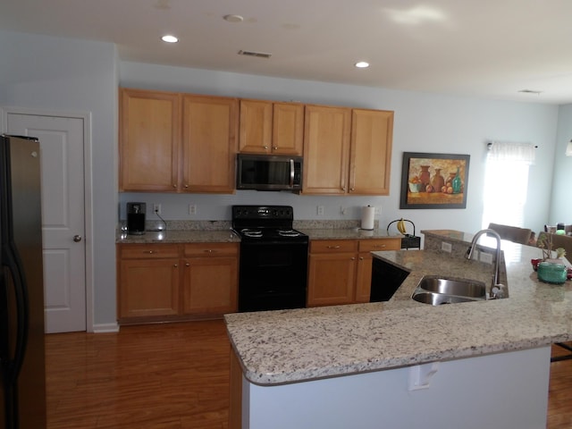 kitchen featuring stainless steel appliances, a sink, a breakfast bar area, and wood finished floors