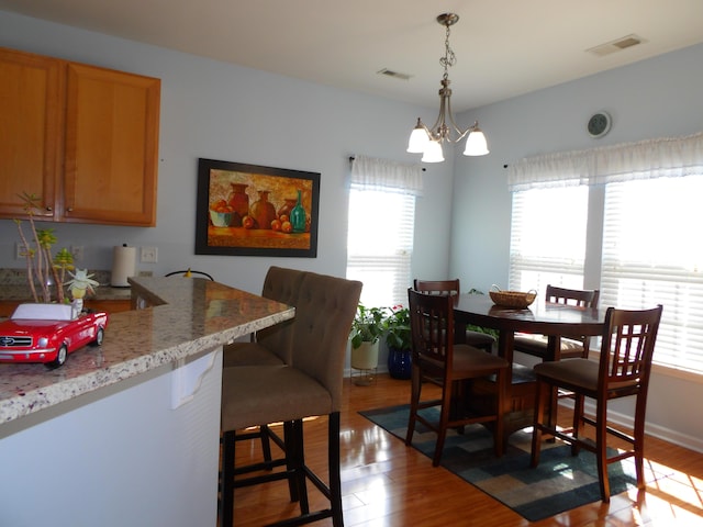 dining space featuring light wood-style flooring, visible vents, and a notable chandelier