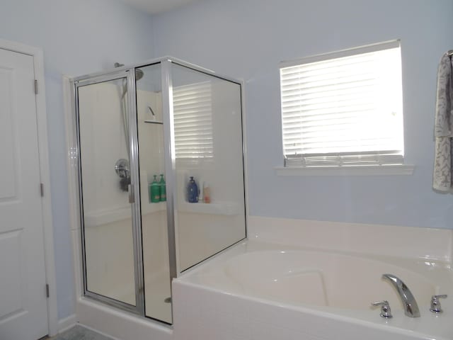 bathroom featuring a stall shower and a bath