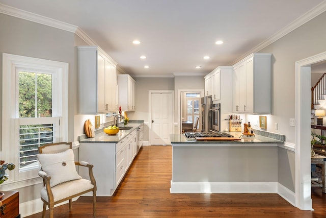 kitchen featuring white cabinetry, ornamental molding, wood-type flooring, and sink