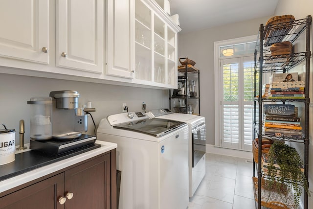 laundry room featuring cabinets, light tile patterned flooring, and washer and clothes dryer