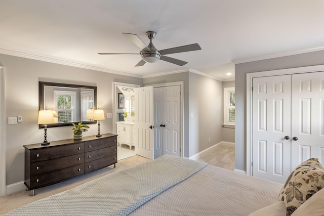 carpeted bedroom with ensuite bathroom, two closets, ceiling fan, and crown molding