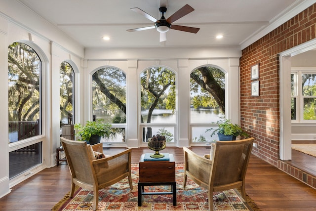 sunroom / solarium featuring a water view and ceiling fan