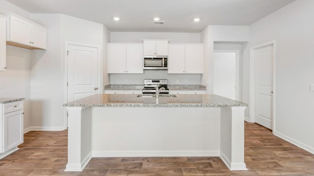 54 Twickenham Loop, Yemassee, SC 29945 - kitchen with stainless steel microwave, range with electric cooktop, an island with sink, white cabinets, and recessed lighting