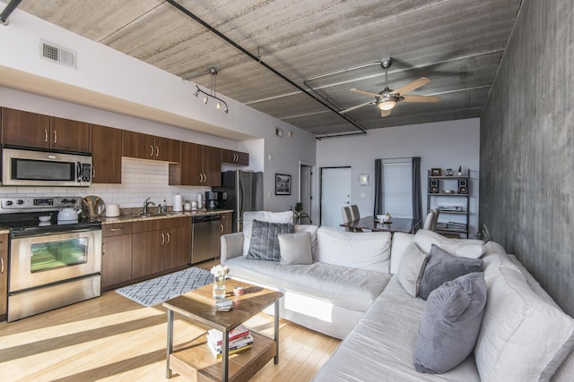 living room featuring sink, ceiling fan, and light hardwood / wood-style flooring