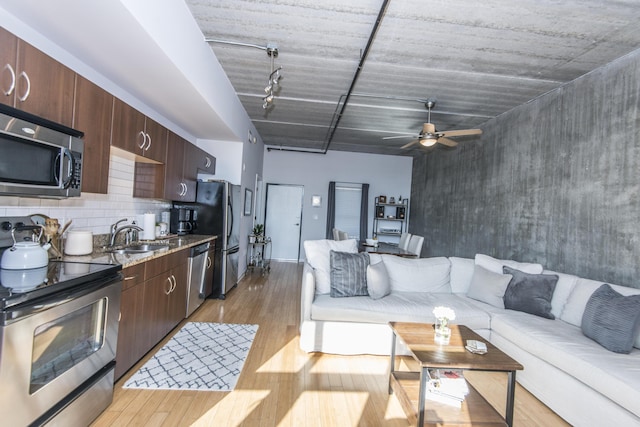 living room featuring light wood-type flooring, rail lighting, ceiling fan, and sink