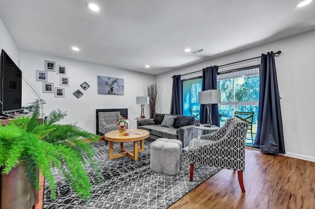 living area featuring baseboards, visible vents, wood finished floors, and recessed lighting