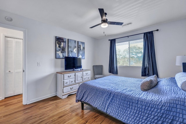 bedroom with light wood-style floors, visible vents, baseboards, and ceiling fan