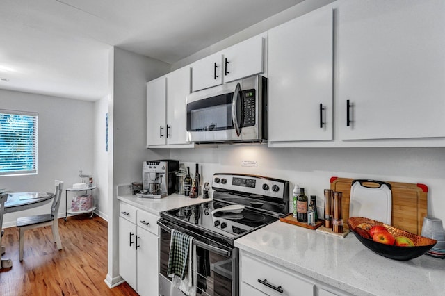 kitchen with light wood-type flooring, baseboards, white cabinetry, and stainless steel appliances