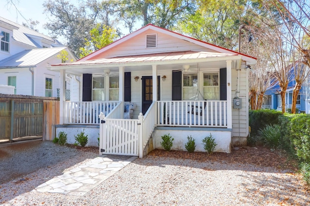 bungalow-style house with metal roof, a gate, fence, and a porch