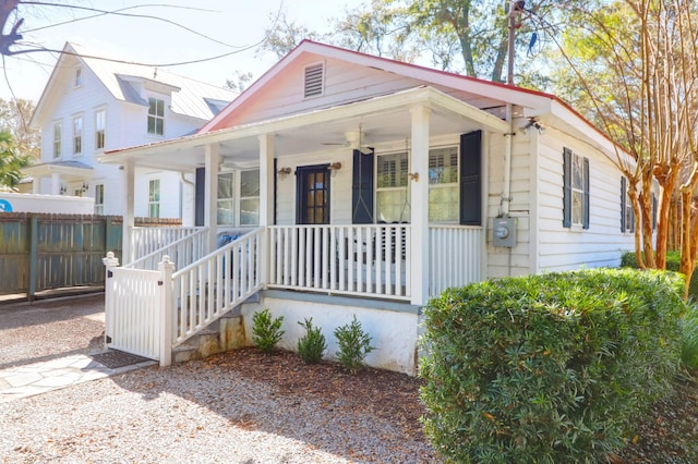 bungalow-style house featuring metal roof, a porch, fence, and a ceiling fan