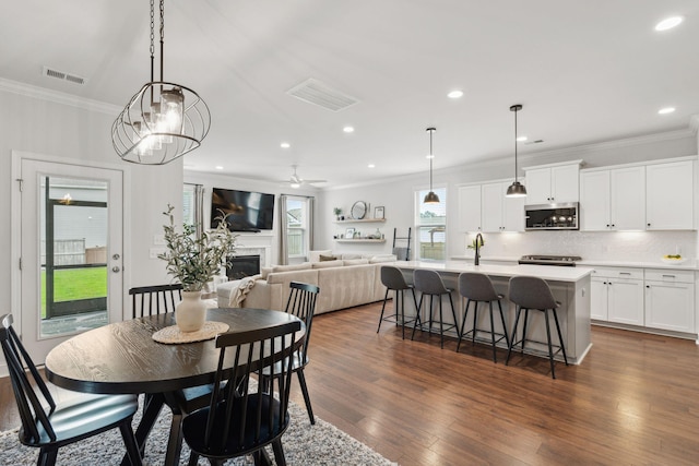 2267 Kemmerlin St, Johns Island, SC 29455 - dining area with ornamental molding, dark wood-style flooring, a fireplace, a ceiling fan, and recessed lighting