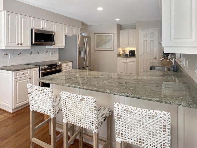 2655 Gnarled Pne, Seabrook Island, SC 29455 - kitchen with appliances with stainless steel finishes, a sink, a peninsula, white cabinets, and a breakfast bar