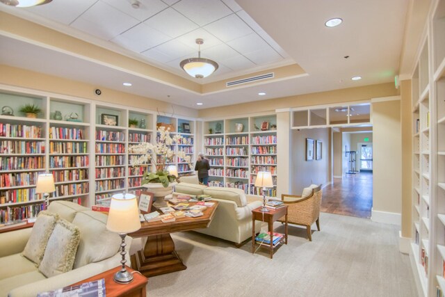 2655 Gnarled Pne, Seabrook Island, SC 29455 - living area featuring bookshelves, a tray ceiling, recessed lighting, carpet flooring, and baseboards