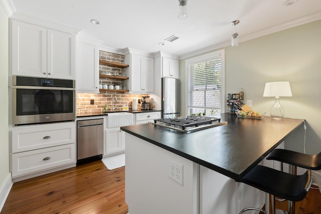 4855 Retriever Rd, Wadmalaw Island, SC 29487 - kitchen featuring stainless steel appliances, dark countertops, open shelves, crown molding, and a breakfast bar