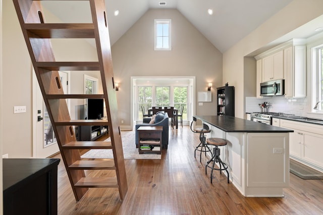 4855 Retriever Rd, Wadmalaw Island, SC 29487 - kitchen with appliances with stainless steel finishes, dark countertops, a kitchen bar, white cabinets, and wood finished floors