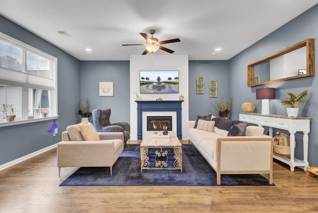 living room featuring ceiling fan, a fireplace, and dark hardwood / wood-style floors