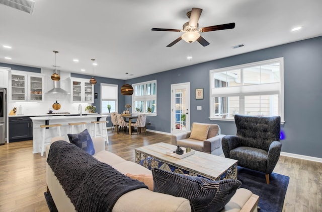 living room with ceiling fan, plenty of natural light, and light hardwood / wood-style floors