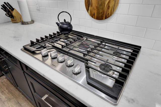 room details featuring wood-type flooring, tasteful backsplash, and stainless steel gas cooktop