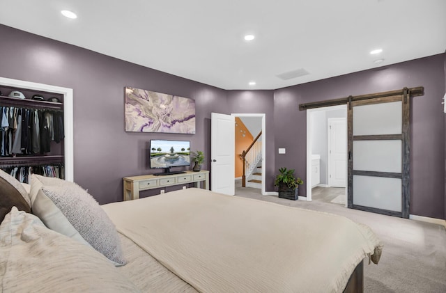 carpeted bedroom with a barn door and a closet