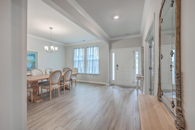 foyer with a notable chandelier, crown molding, and light hardwood / wood-style floors