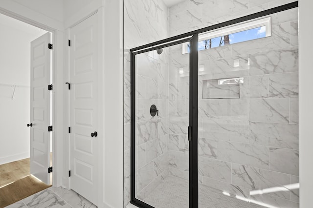 full bathroom with marble finish floor, a shower stall, and baseboards