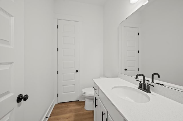 bathroom featuring toilet, wood finished floors, and vanity