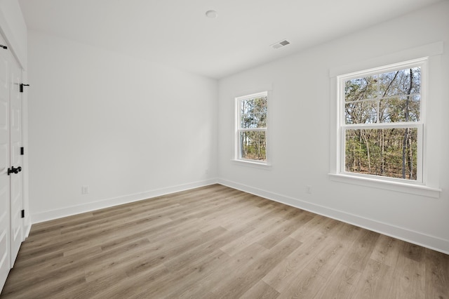 unfurnished room featuring light wood-type flooring, baseboards, and visible vents