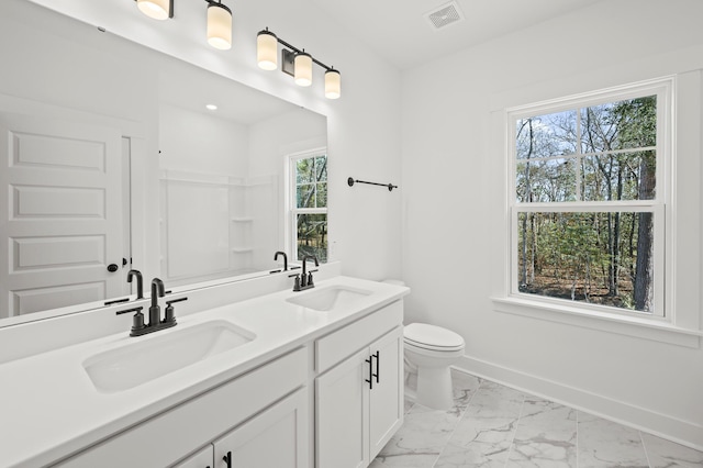 bathroom with toilet, marble finish floor, baseboards, and a sink