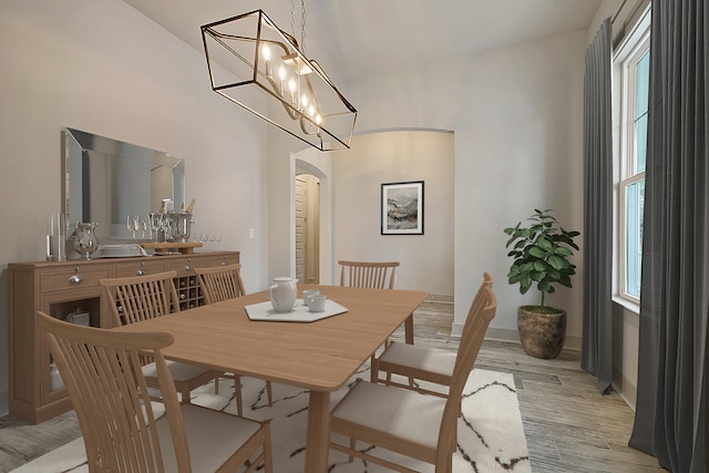 dining area with arched walkways, light wood-type flooring, and baseboards