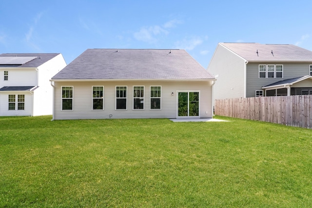 rear view of property featuring a lawn, fence, and a patio