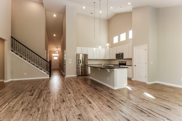 kitchen featuring dark countertops, light wood finished floors, high vaulted ceiling, stainless steel appliances, and open floor plan