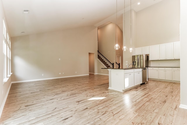 kitchen with visible vents, high vaulted ceiling, white cabinetry, light wood-style flooring, and stainless steel appliances