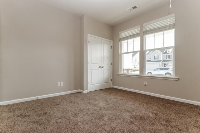 unfurnished bedroom with carpet floors, baseboards, visible vents, and a closet