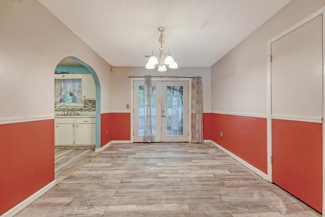 4606 Moss Ct, North Charleston, SC 29420 - entryway with light wood-style floors, french doors, a textured ceiling, a chandelier, and arched walkways
