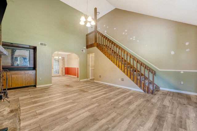4606 Moss Ct, North Charleston, SC 29420 - unfurnished living room with a chandelier, arched walkways, high vaulted ceiling, light wood finished floors, and stairway