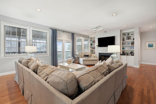 living room featuring hardwood / wood-style floors, built in features, and ceiling fan