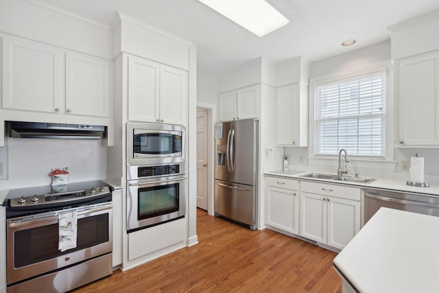 kitchen with sink, light hardwood / wood-style floors, white cabinets, and appliances with stainless steel finishes